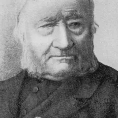 Portret Jana Dzierżona, pszczelarza z charakterystyczną brodą i siwymi włosami, w ciemnym stroju.