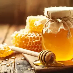 Słoik złocistego miodu, plastry miodu i rumianek. Zastanawiasz się, jaki miód na refluks jest najlepszy? Ten naturalny produkt może przynieść ulgę.
