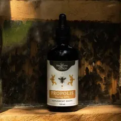 Butelka propolisu na tle ula. Zastanawiasz się, jak długo można stosować propolis? Ten naturalny produkt pszczeli jest cennym wsparciem.