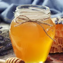 Słoik złocistego miodu, plastry miodu i lawenda. Naturalny sposób na przeziębienie, jak podawać miód na przeziębienie.