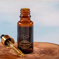 Propolis na zapalenie jelita grubego. Krople z propolisu w buteleczce z pipetą, na drewnianym tle.