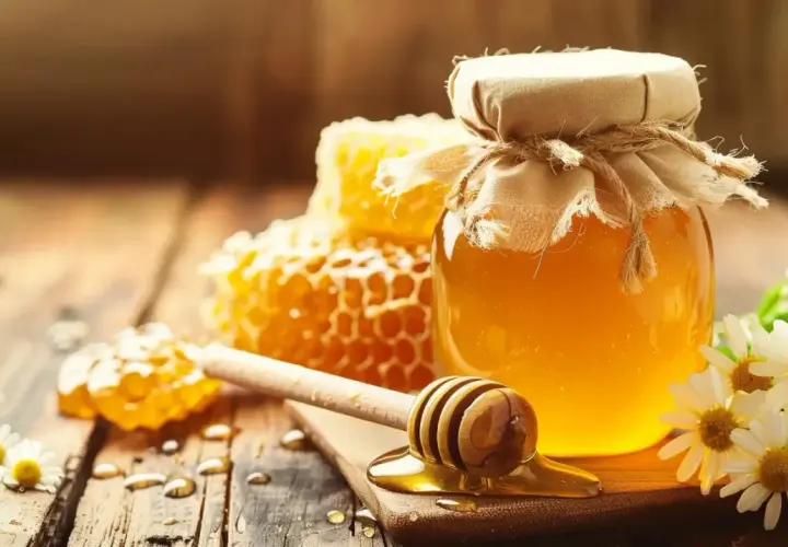 Słoik złocistego miodu, plastry miodu i rumianek. Zastanawiasz się, jaki miód na refluks jest najlepszy? Ten naturalny produkt może przynieść ulgę.