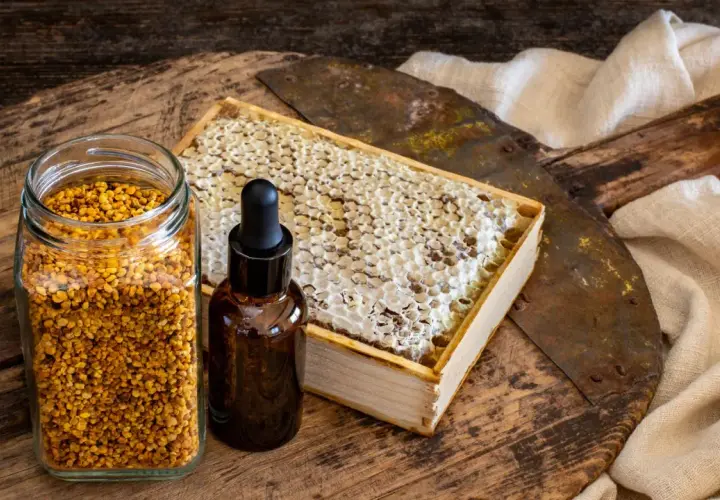 Słoik z pyłkiem pszczelim, buteleczka z kroplomierzem i plaster miodu. Naturalne składniki, które mogą posłużyć jako propolis lek.