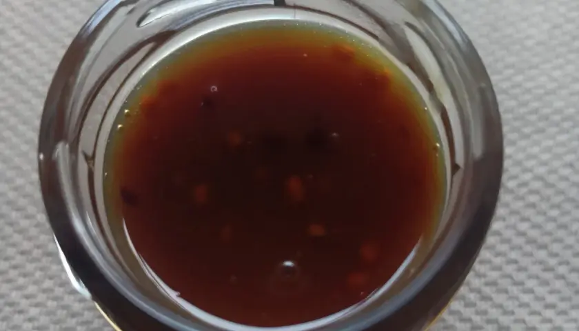 Ciemnobrązowy płyn w szklanym naczyniu, być może wskazówka, jak stosować propolis na gronkowca.