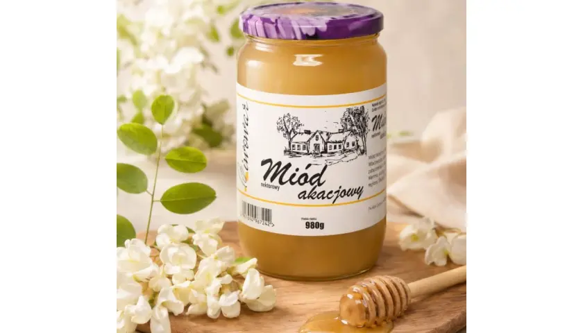 Słoik miodu akacjowego, obok gałązki akacji i drewniana chochla z miodem.