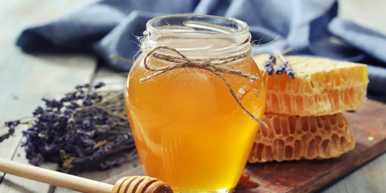 Słoik złocistego miodu, plastry miodu i lawenda. Naturalny sposób na przeziębienie, jak podawać miód na przeziębienie.